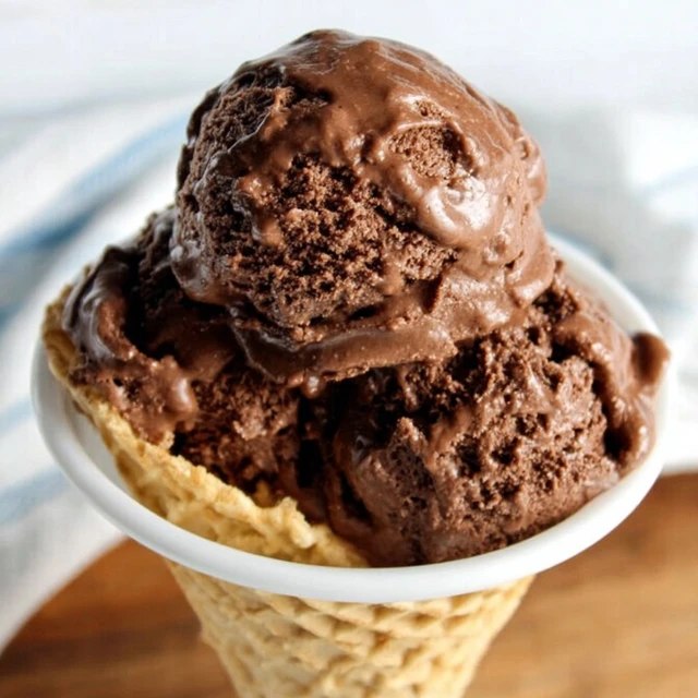 Close-up of a single scoop showing dense fudgy texture, deep brown color, slight glossy melt edge