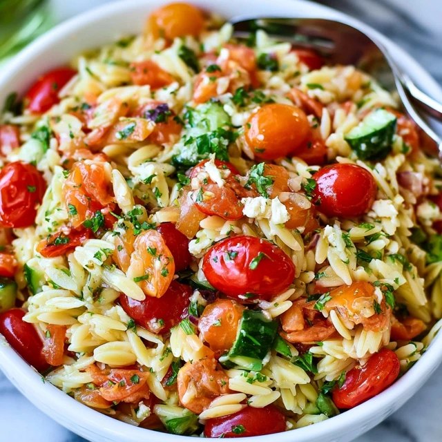 Close-up of Mediterranean orzo salad showing the little rice-shaped pasta coated in dressing with colorful vegetables and feta